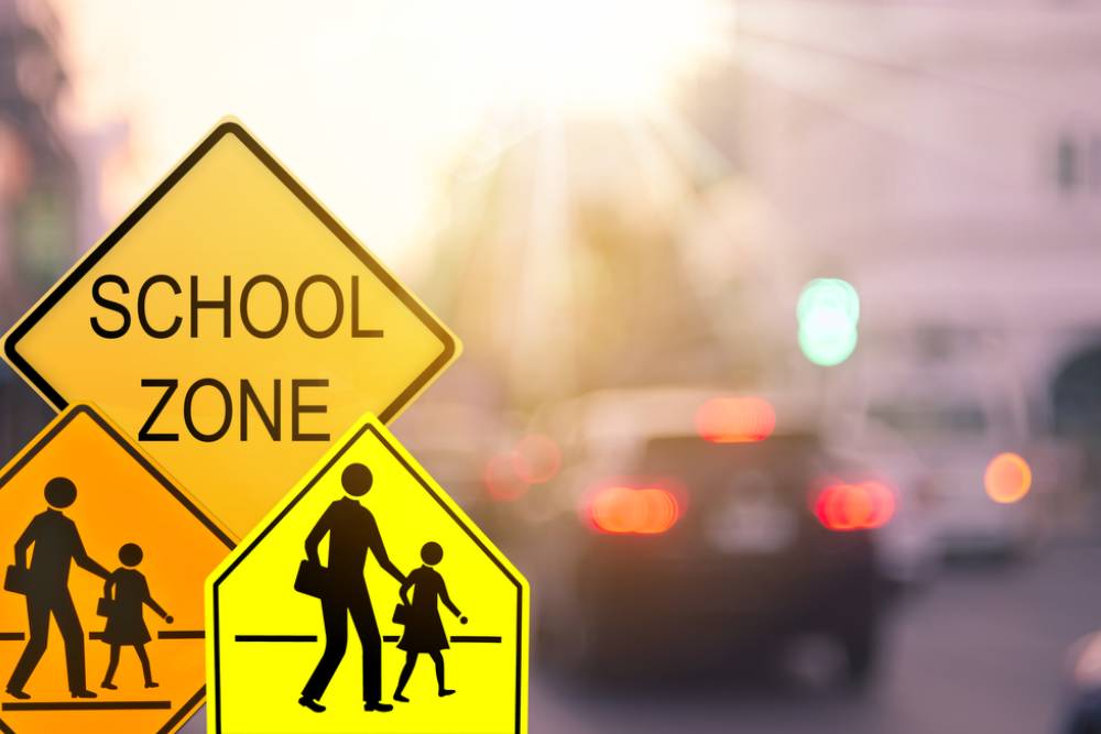 Set of School zone warning sign on blur traffic road with colorful bokeh light abstract background